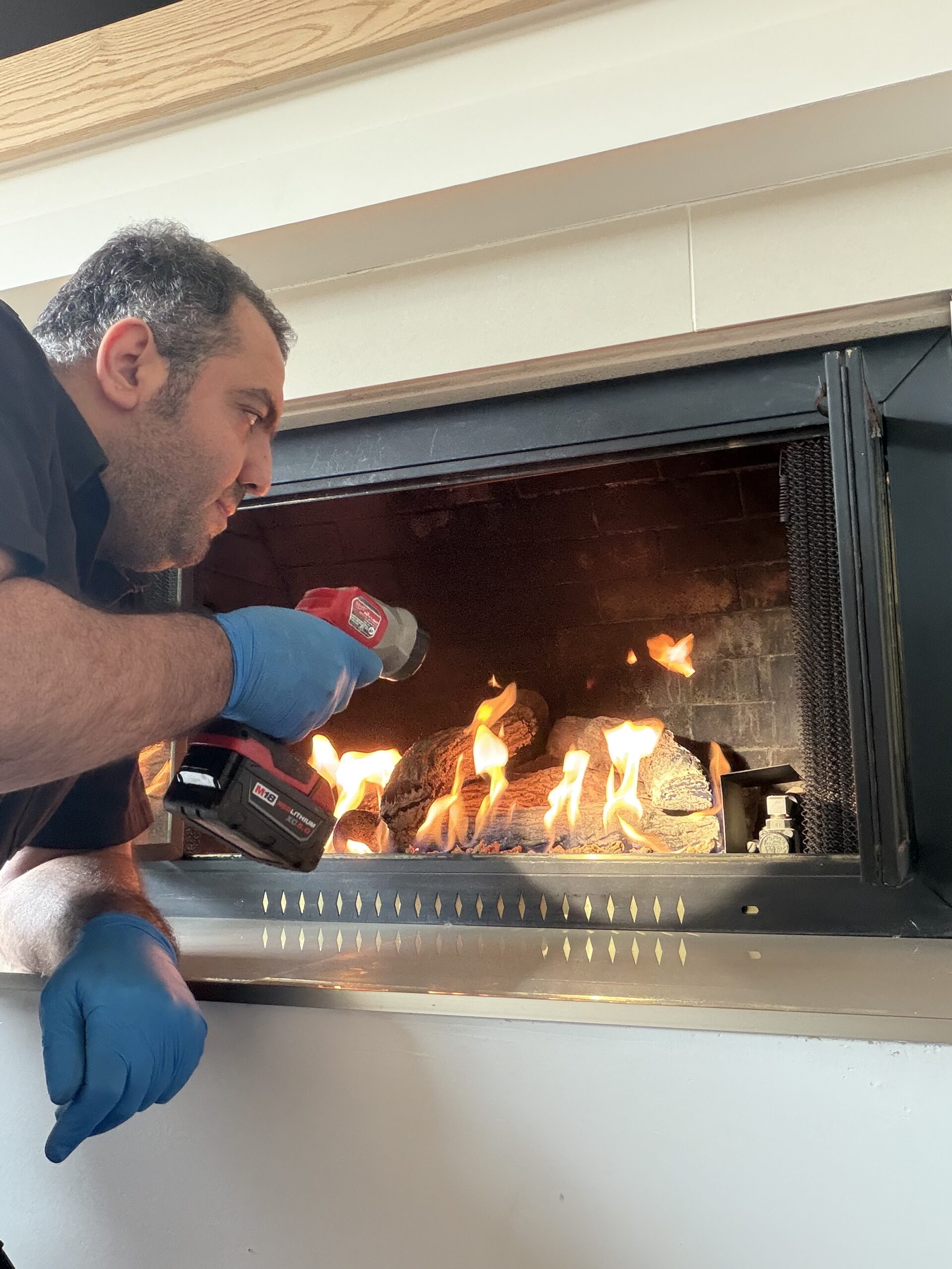 Technician performing gas fireplace service and safety check