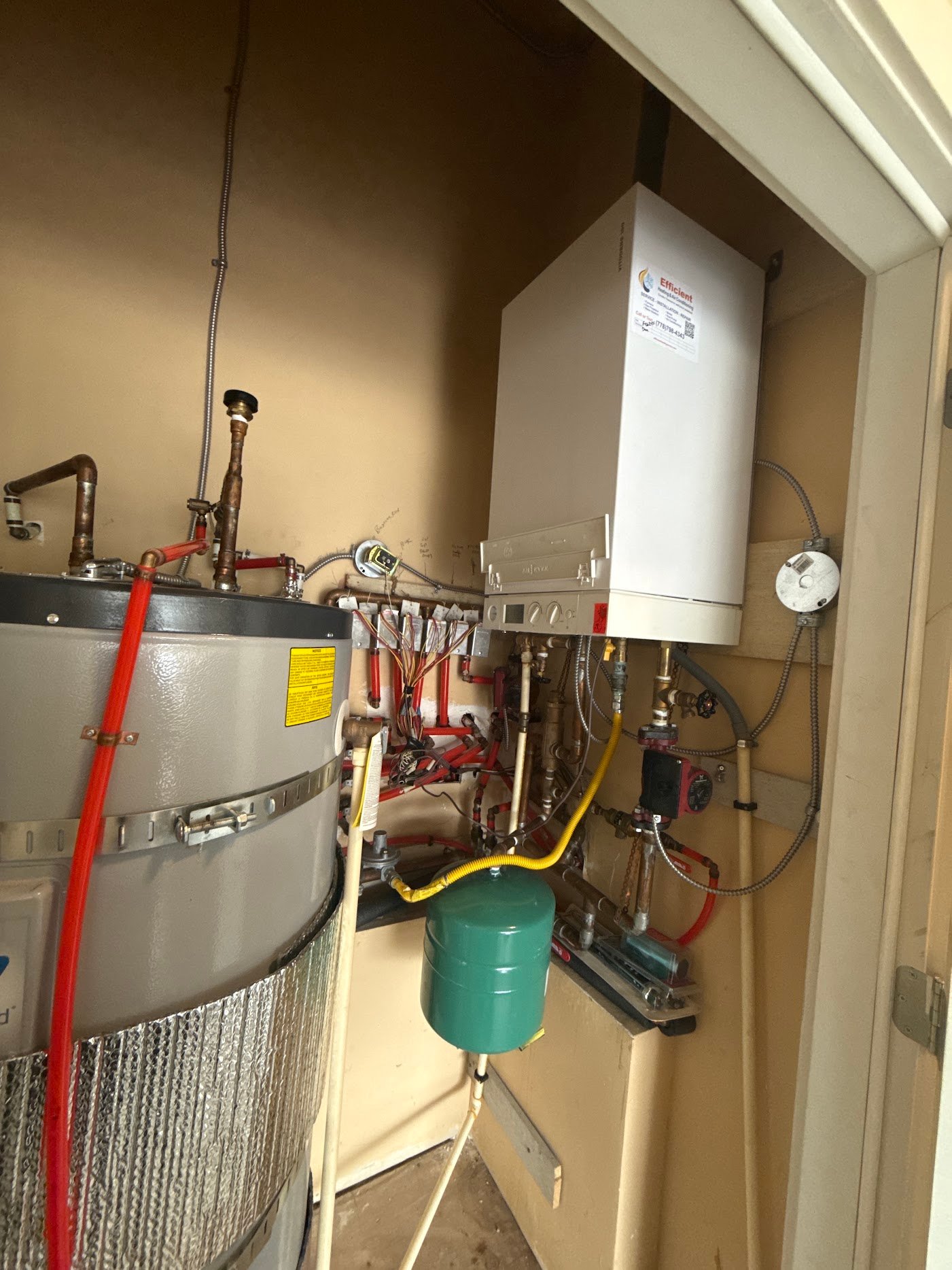 Wall-mounted boiler beside a storage tank, with a circulator, green expansion vessel and connected pipework